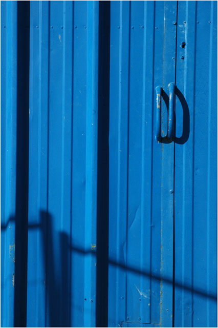 BLOG-DSC_0186-ombre grillage chantier sur porte bleue cabane Meyran